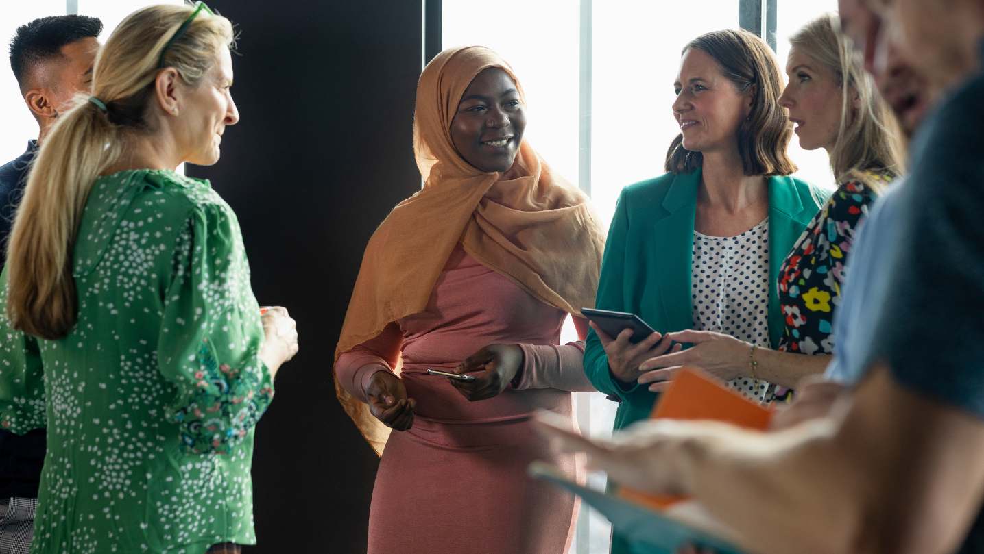 Group of people of various skin tones and genders talking in a group.