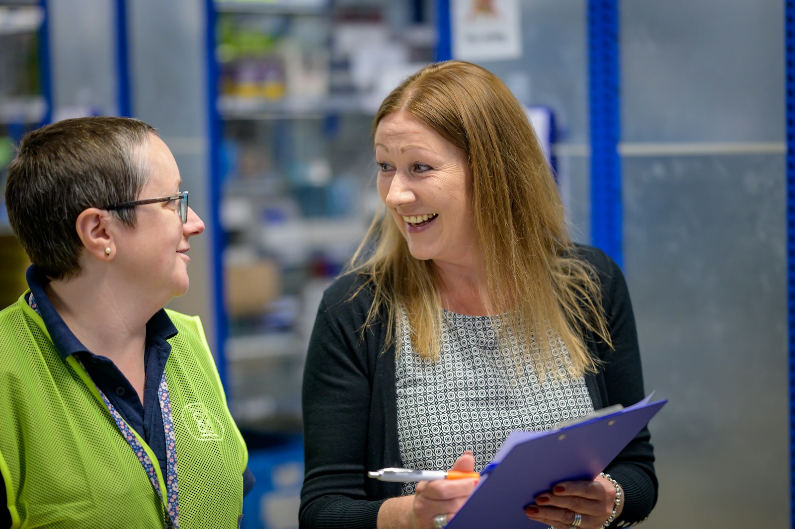 A community health worker with a clipboard talks with another person. 