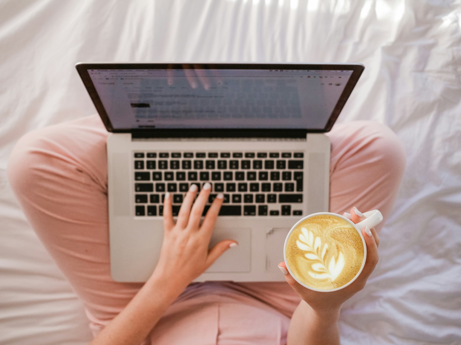 Photo by Sincerely Media person using MacBook Pro and holding cappuccino